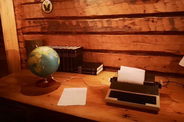 Karttapallo, kirjoja ja kirjoituskone puupöydällä