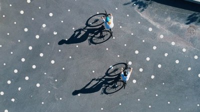 Kaksi pyöräilijää kuvattuna yläperspektiivistä.